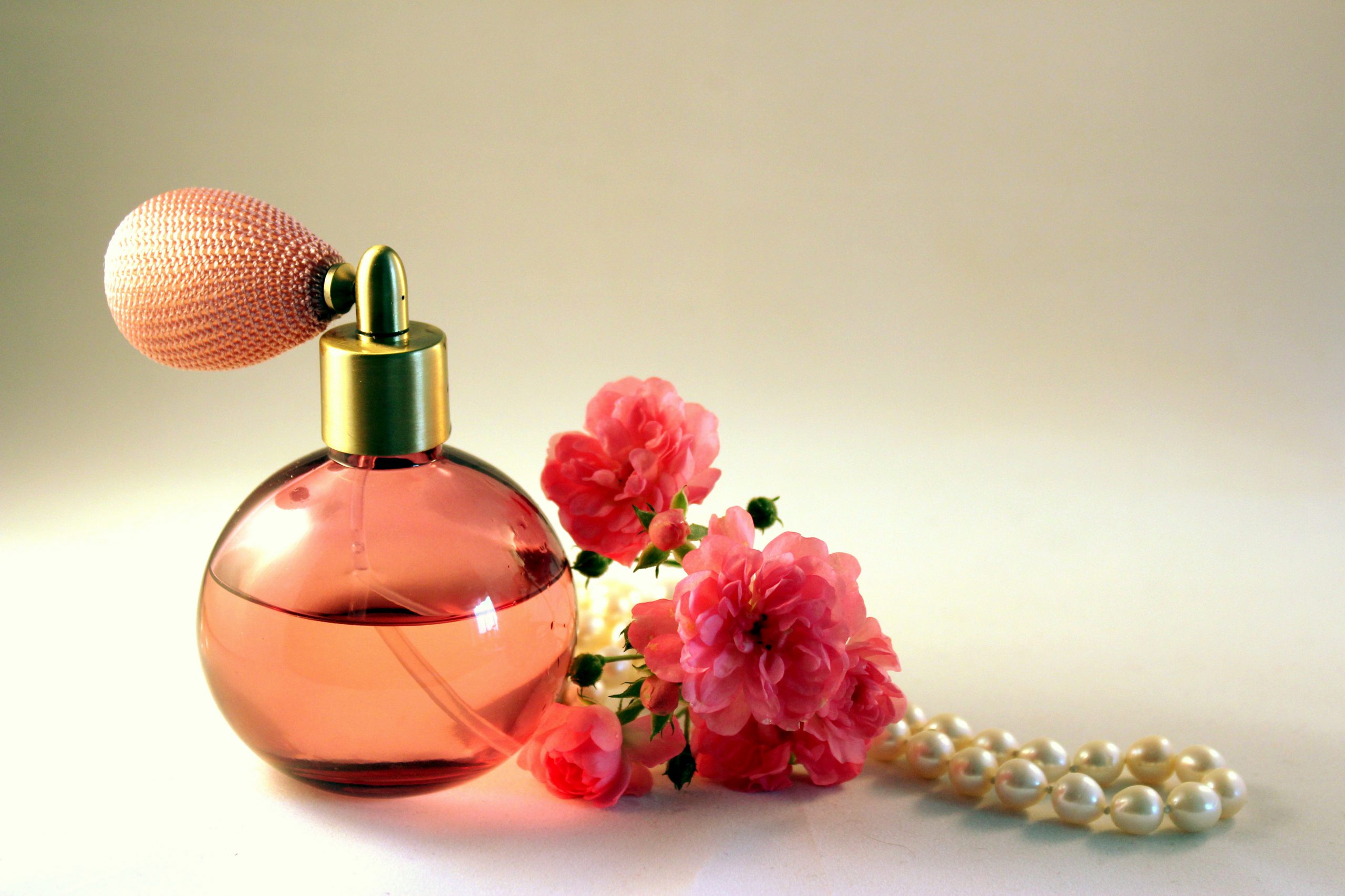 A pink bottle of perfume, next to roses. Not brand specific.